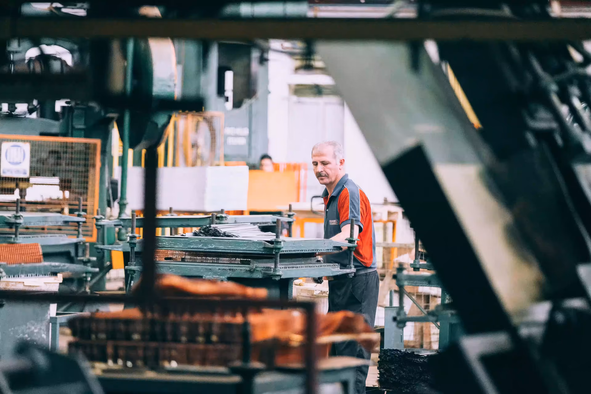 Werker bedient eine Industriemaschine in einer Produktionshalle.
